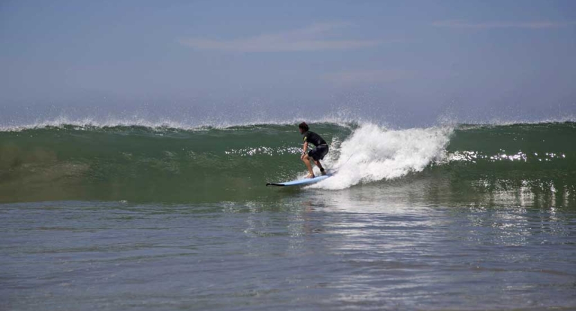 A person surfs a wave under blue skies